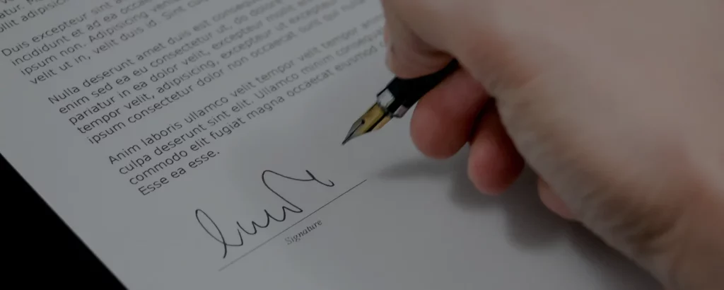 Hand som skriver sin signatur på ett avtal